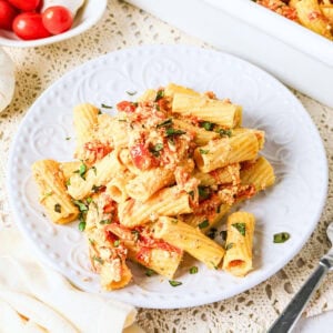 Plate of rigatoni pasta with creamy tomato sauce and fresh basil on top.