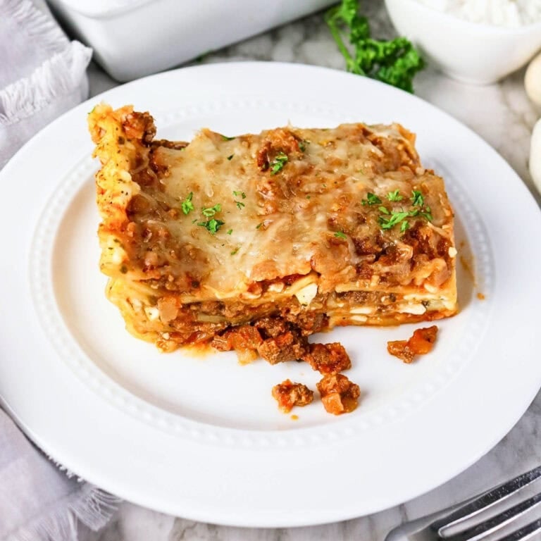 A slice of lasagna with meat sauce and cheese on a white plate.
