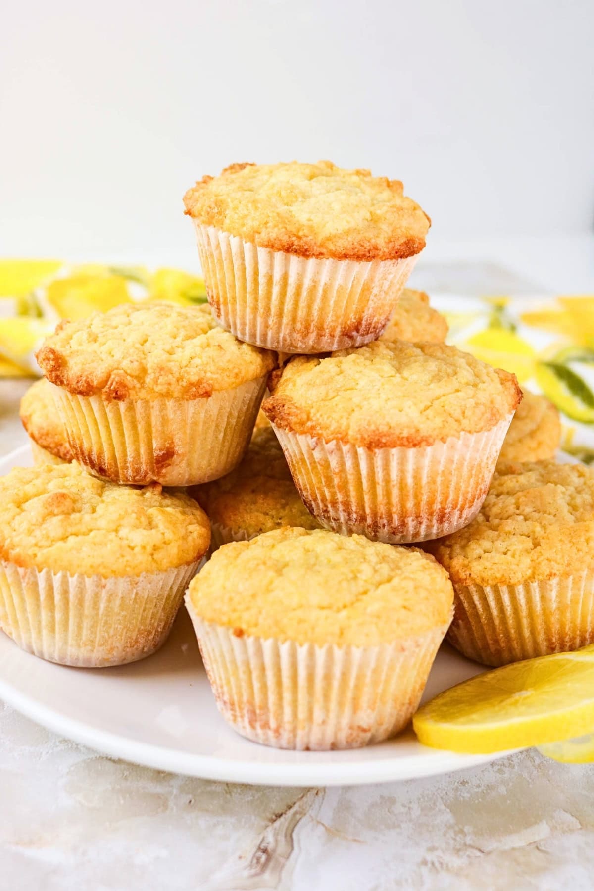 A plate of lemon muffins stacked with lemon slices nearby.