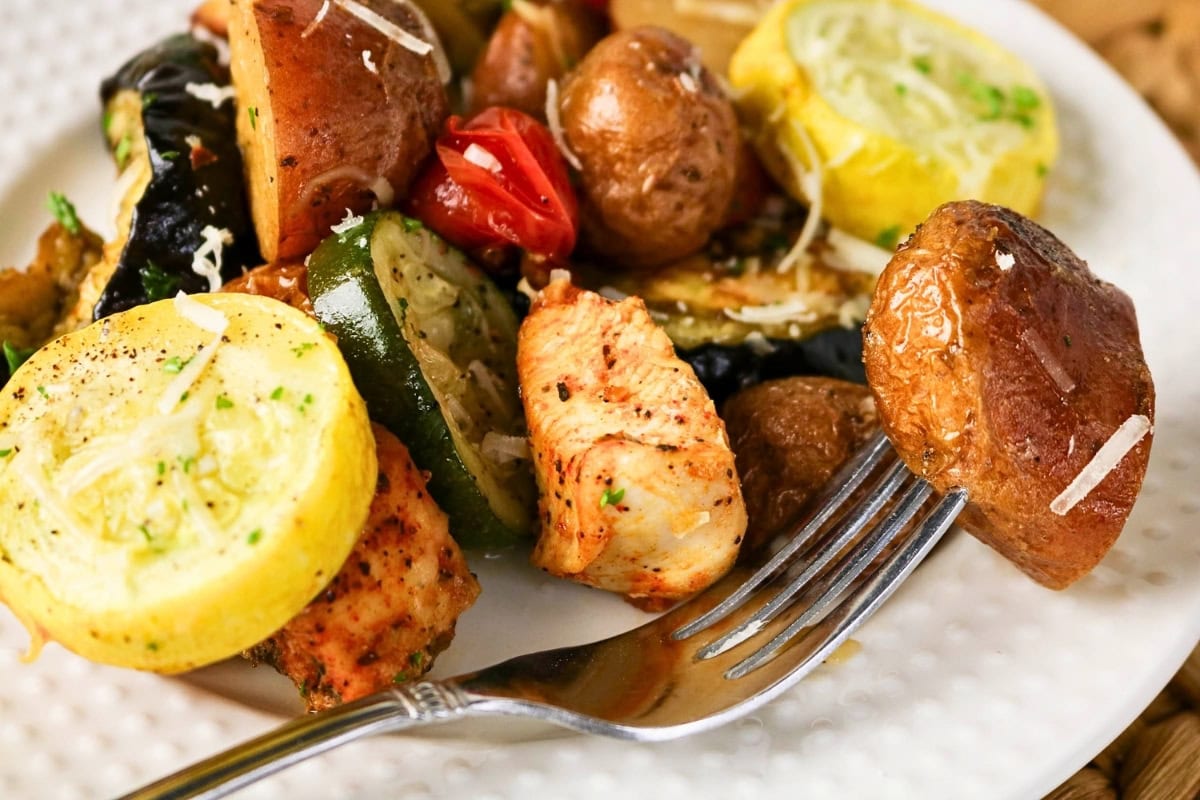 Grilled chicken with roasted squash, zucchini, tomatoes, and potatoes.