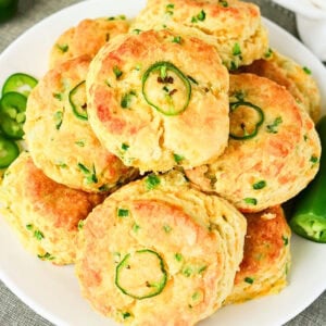 Biscuits with sliced jalapeños and herbs on a white plate.