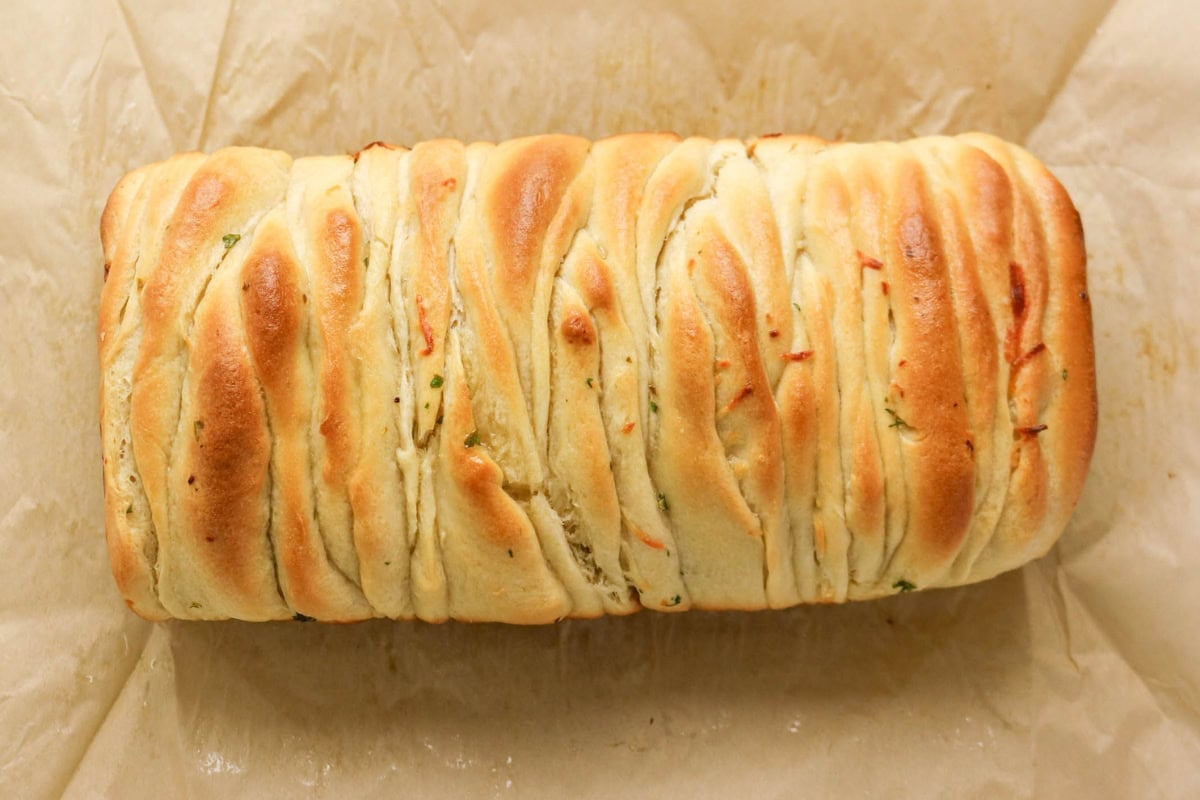 Loaf of pull-apart bread on parchment paper.