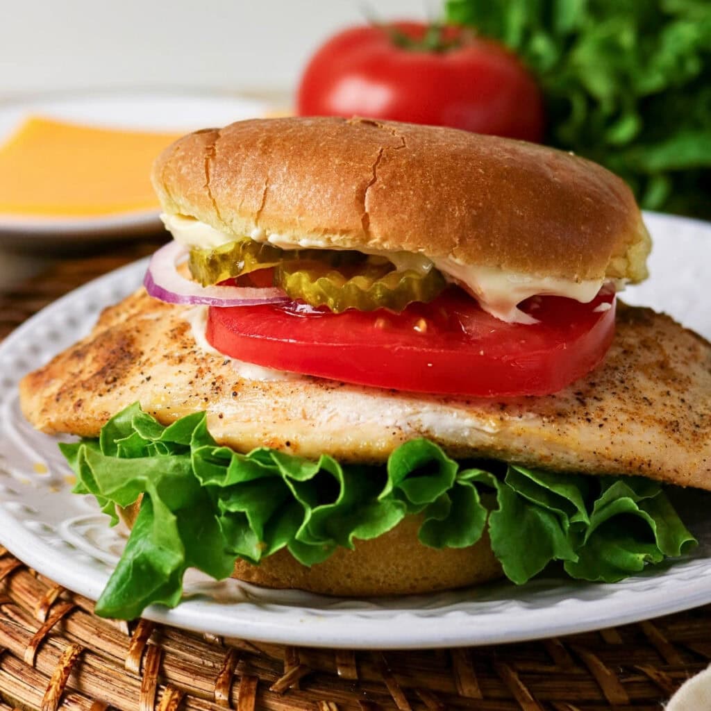 Grilled chicken sandwich with lettuce, tomato, pickles, onion, and mayonnaise.