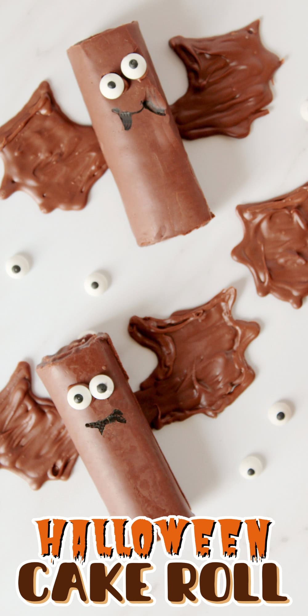 Two chocolate cake rolls decorated as bats with candy eyes and chocolate wings.