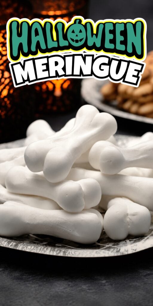 White bone-shaped meringues stacked on a plate, Halloween decor behind.