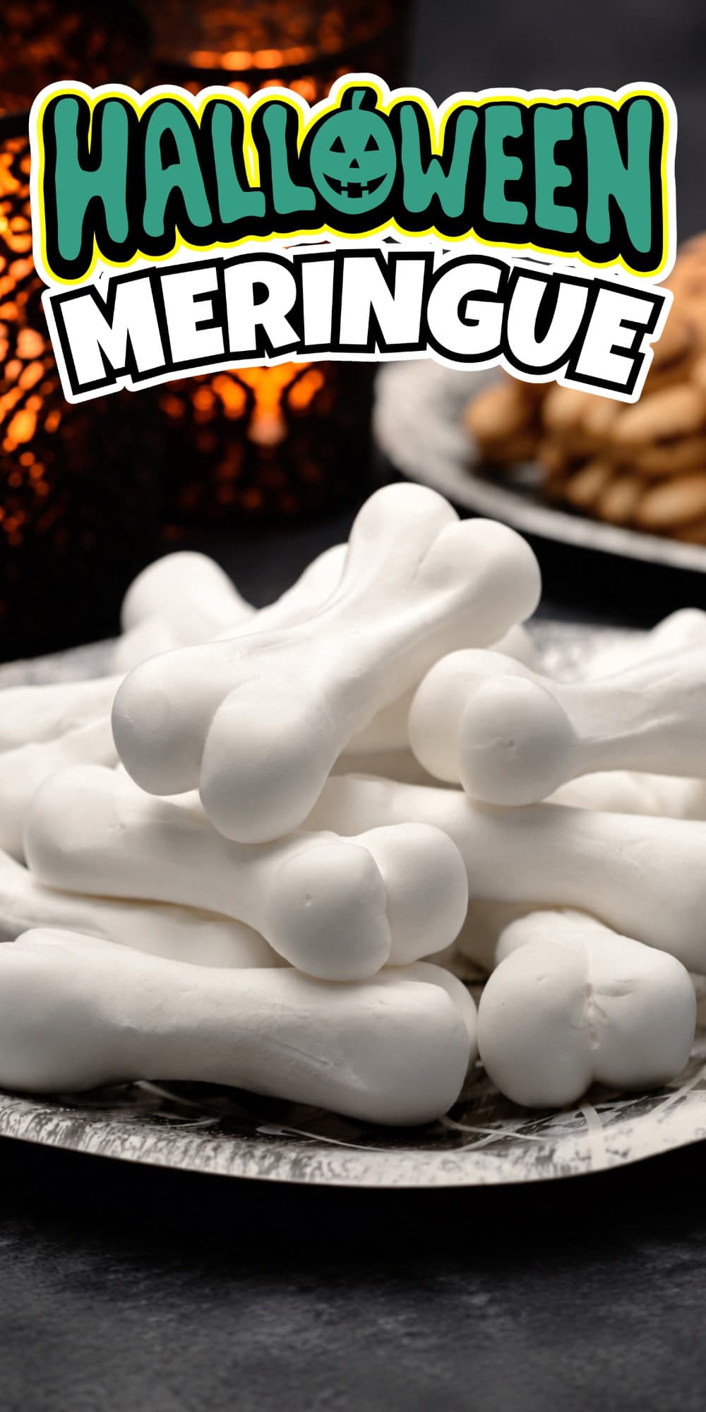 White bone-shaped meringues stacked on a plate, Halloween decor behind.