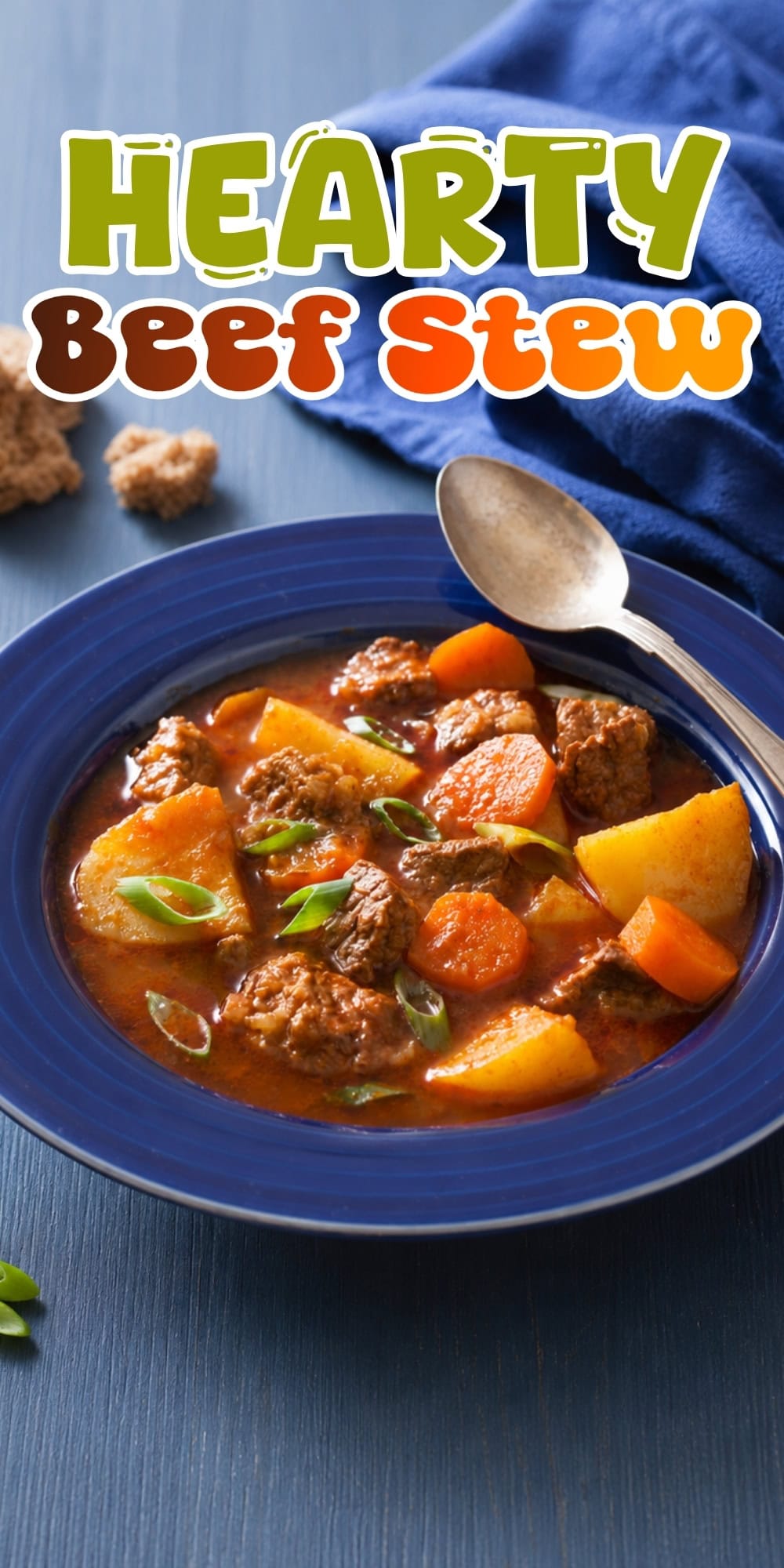 Bowl of beef stew with carrots, potatoes, and a spoon on the side.