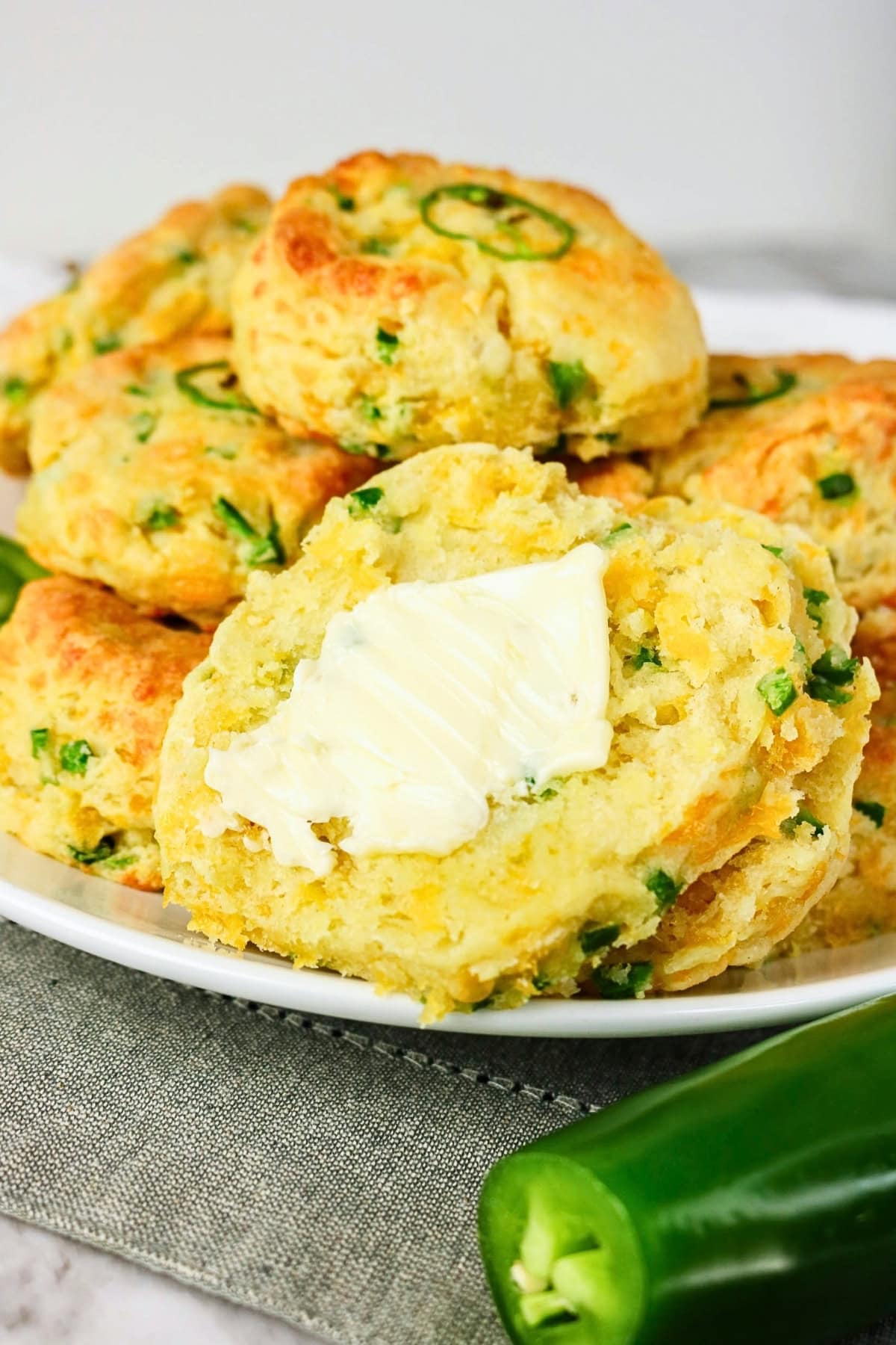 Biscuits with jalapeños, one split open and topped with butter on a plate.