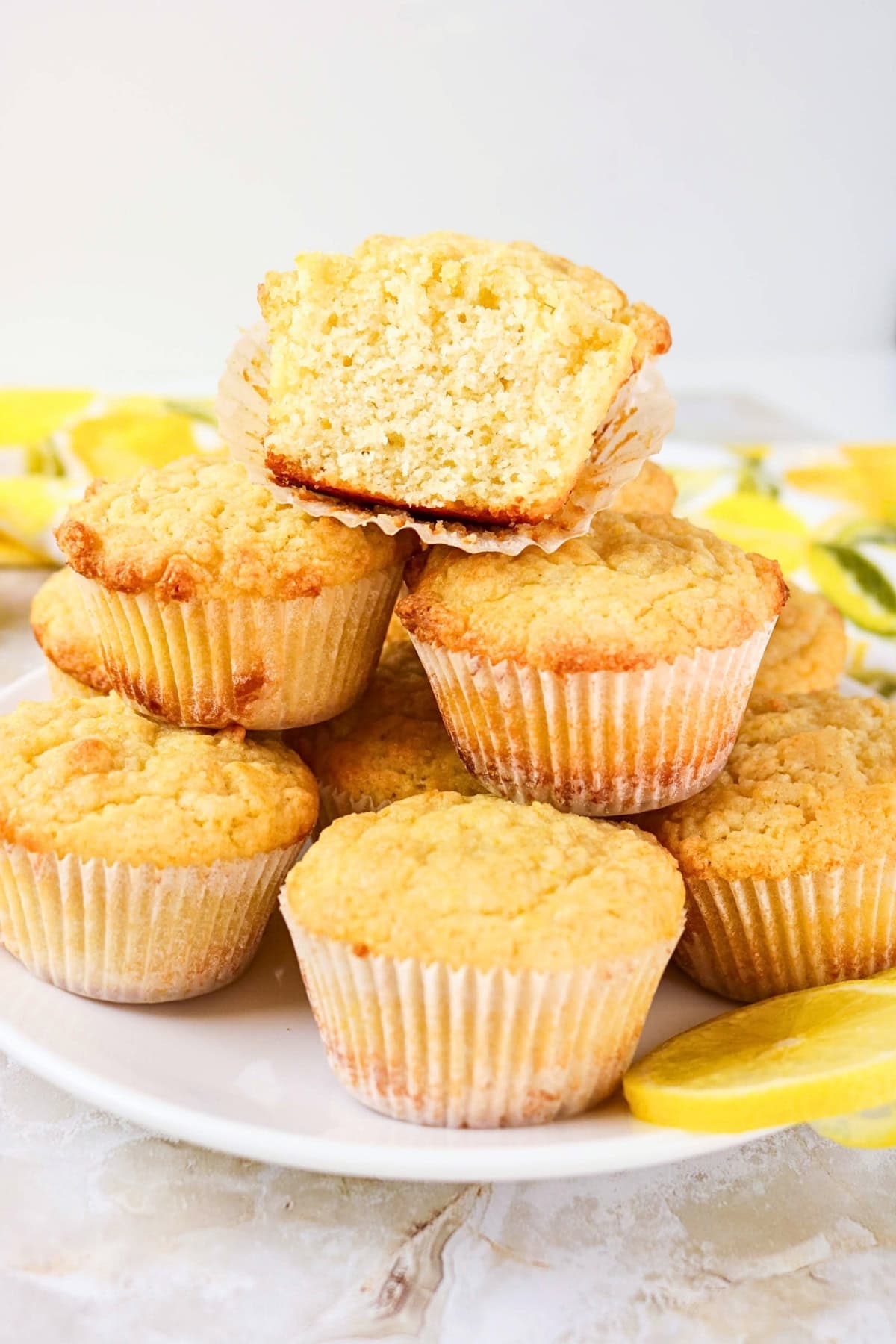 A plate of lemon muffins, one halved to show the soft inside.