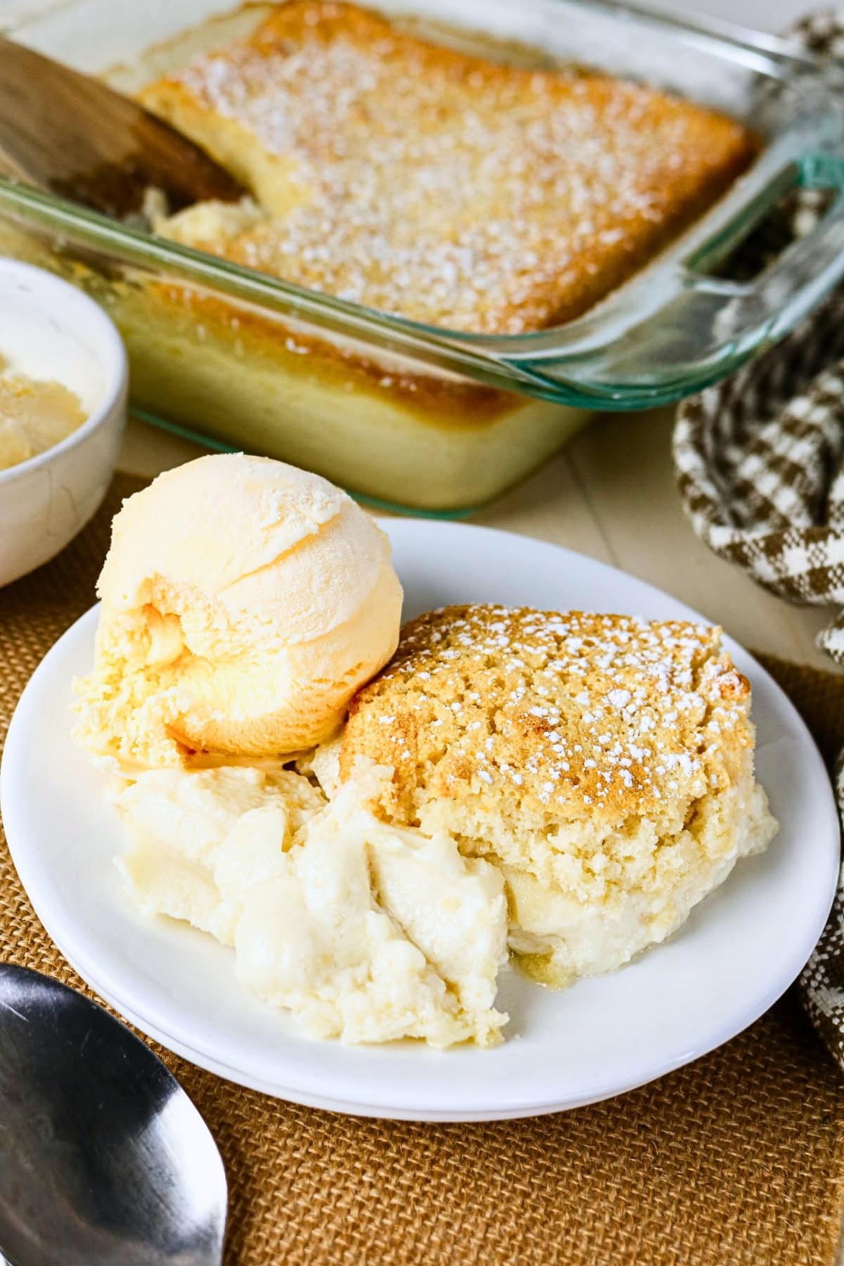 A plate of lemon pudding cake with vanilla ice cream and powdered sugar.