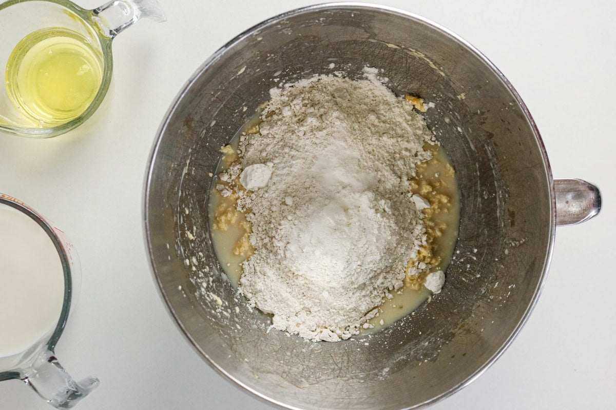 Flour, wet ingredients, and egg white in a mixing bowl on a white surface.