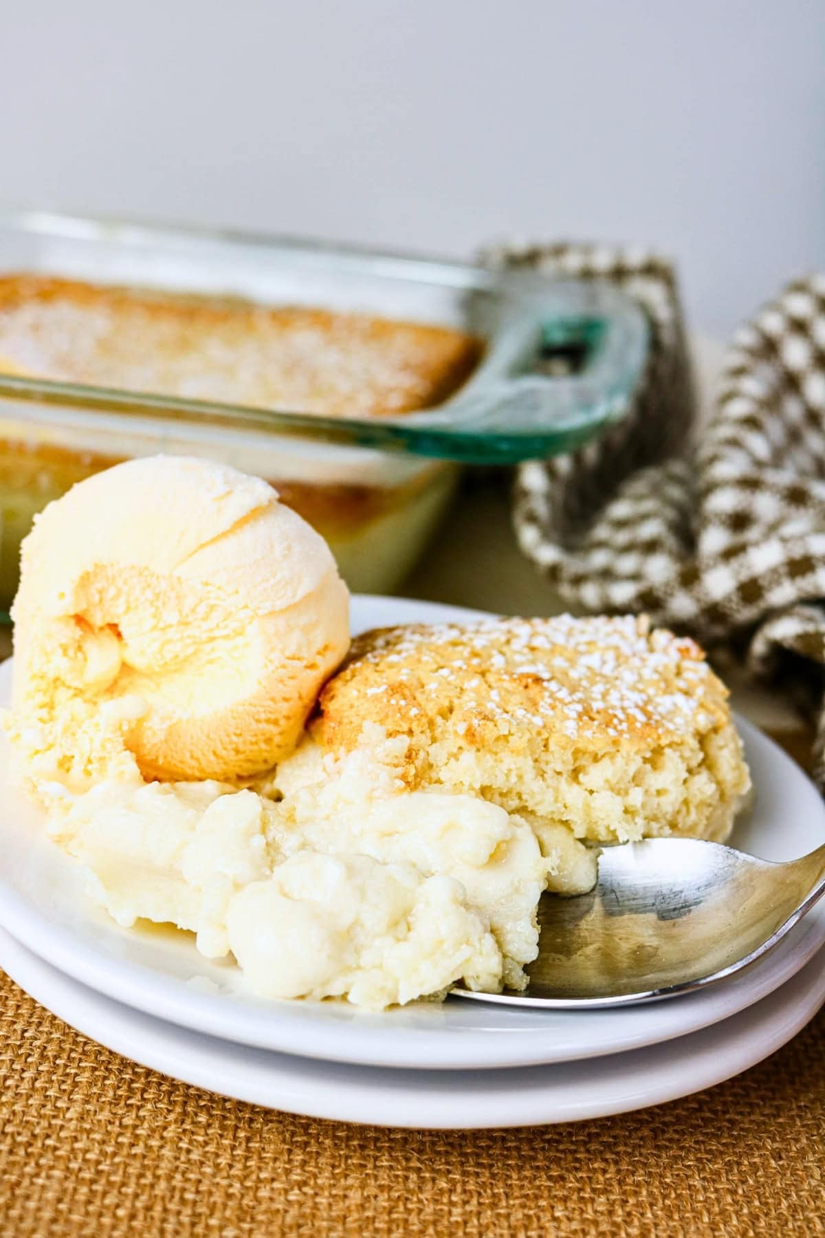 Vanilla ice cream and cobbler dessert on a white plate with a spoon.