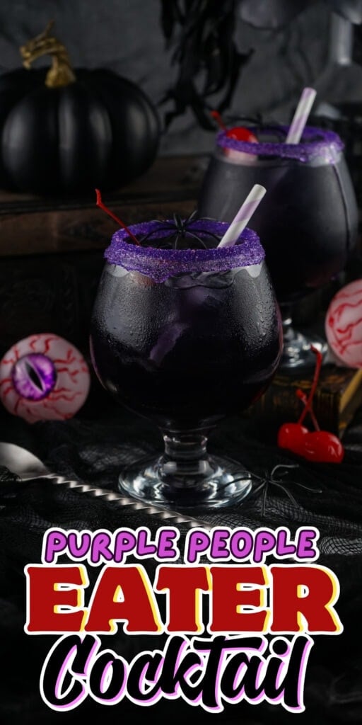 Two dark purple cocktails with purple sugar rims, Halloween decor in background.