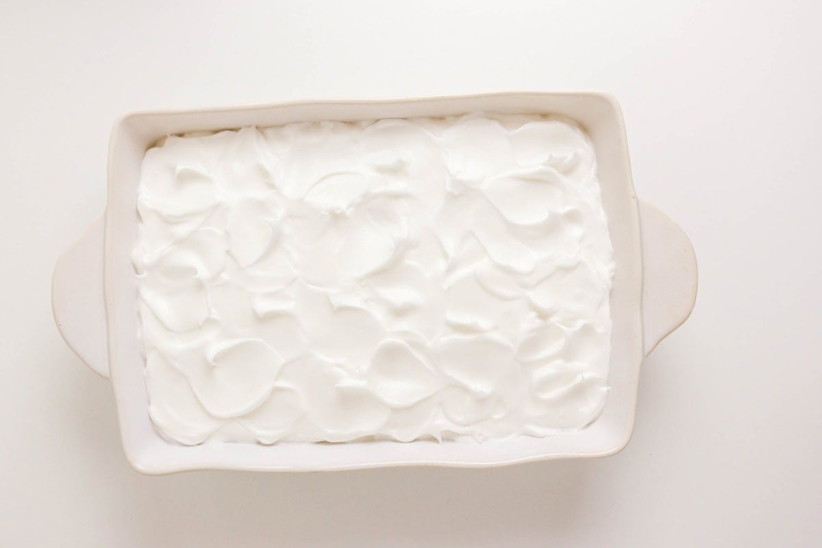 Rectangular dish filled with fluffy white whipped topping on a white background.