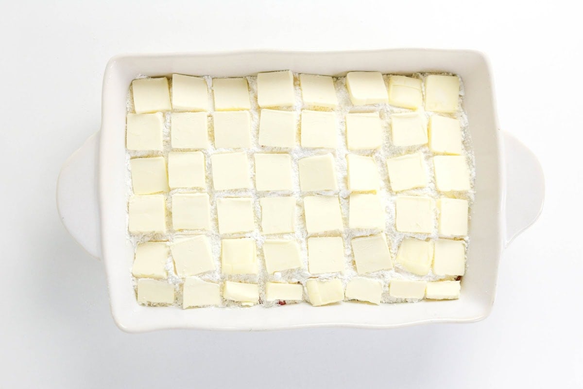Rectangular dish with evenly spaced butter cubes on a white mixture.