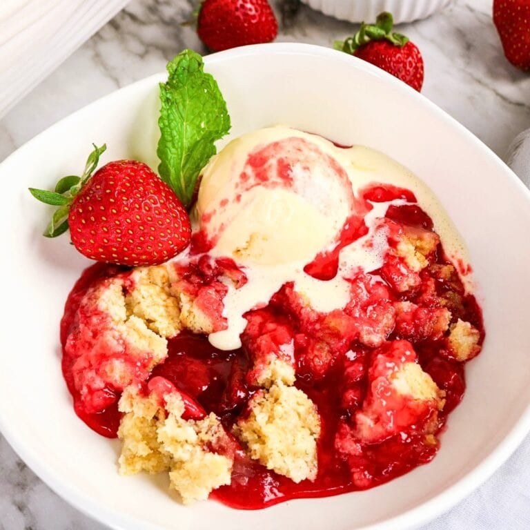 Strawberry crumble with vanilla ice cream and fresh strawberry in a bowl.