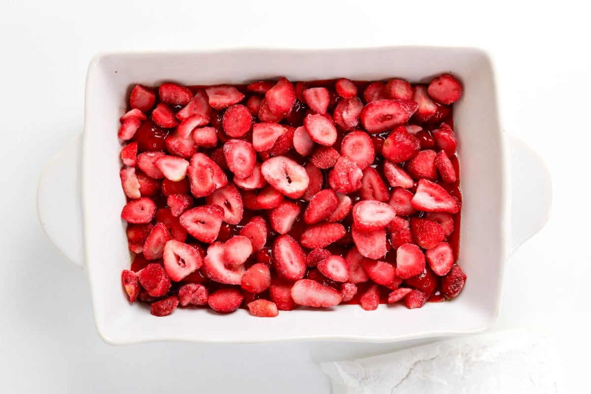 Rectangular dish filled with sliced strawberries on a white background.