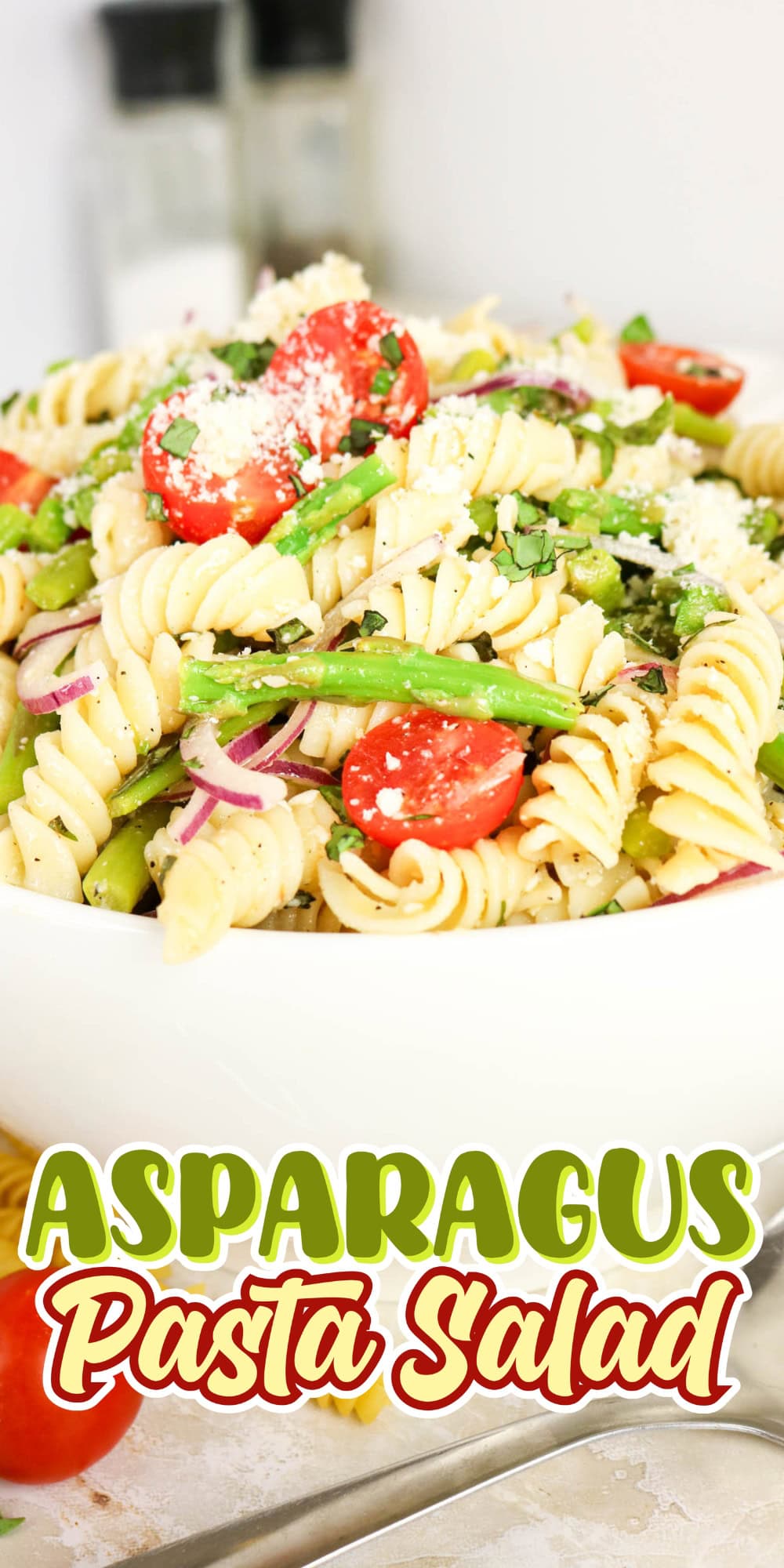 Bowl of pasta salad with asparagus, tomatoes, and parmesan cheese.