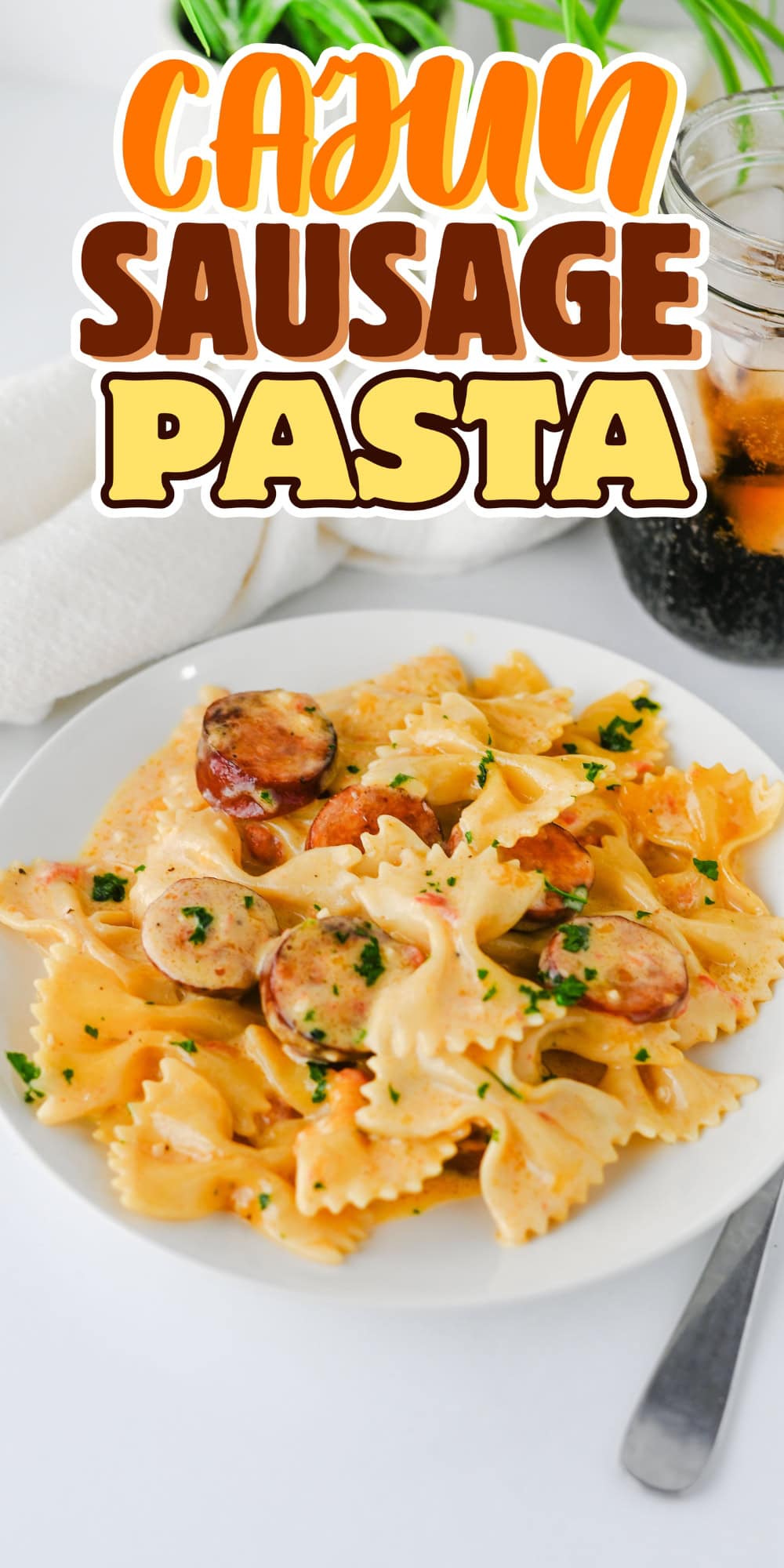Plate of bowtie pasta with sausage, parsley, and a glass of soda nearby.