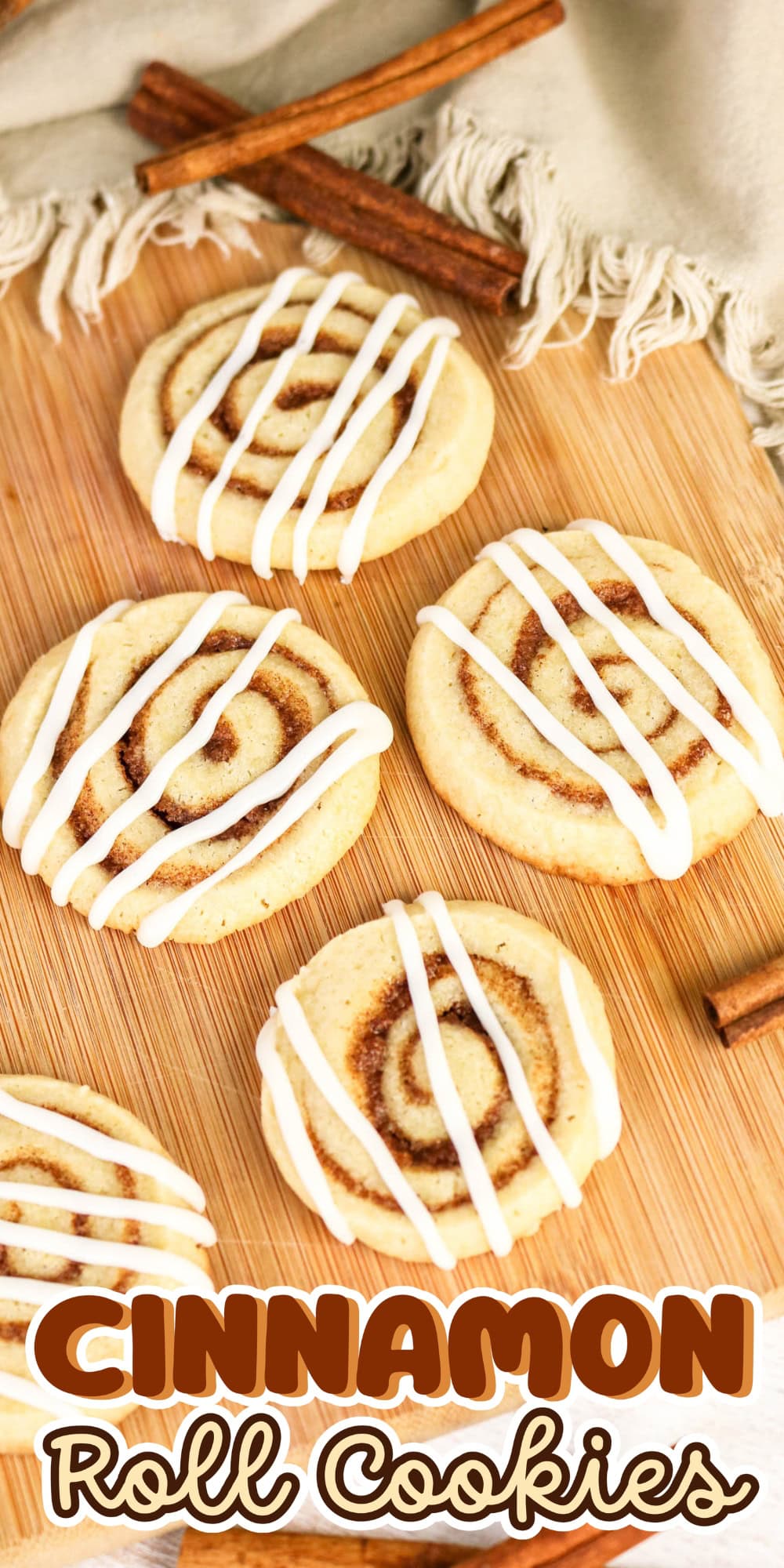 Cinnamon roll cookies with icing and cinnamon sticks on a wooden board.