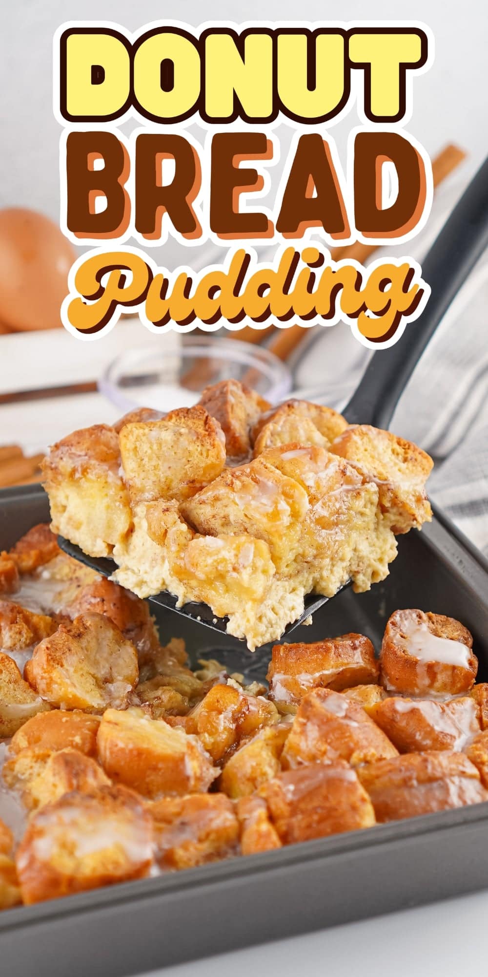 A spatula lifts donut bread pudding from a baking pan.