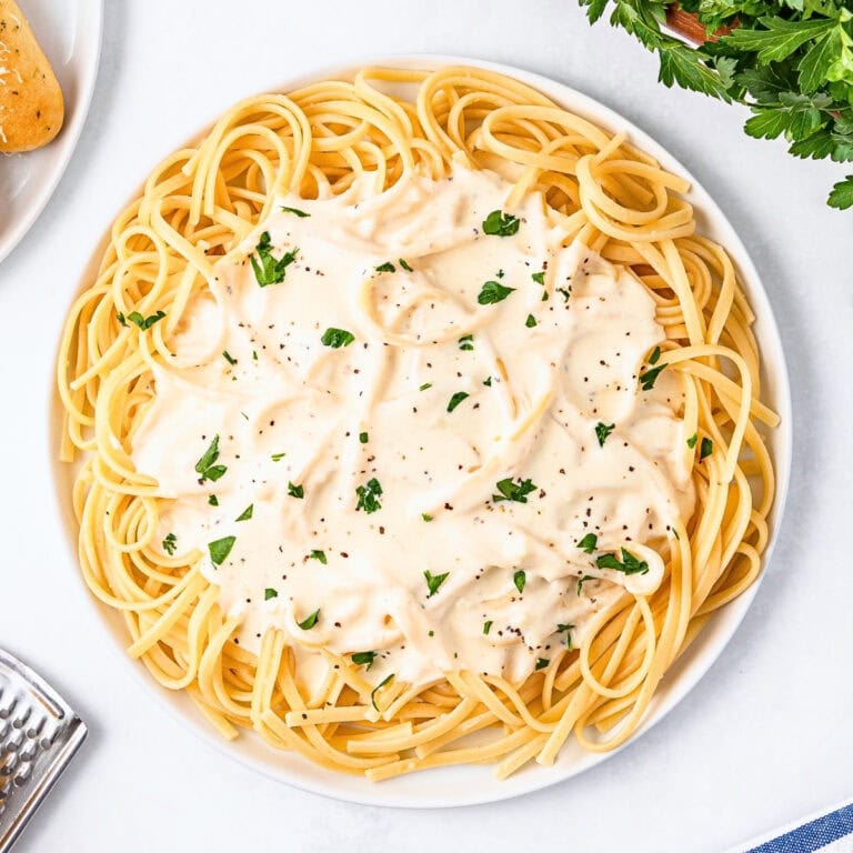 Spaghetti with creamy white sauce, garnished with parsley and black pepper.