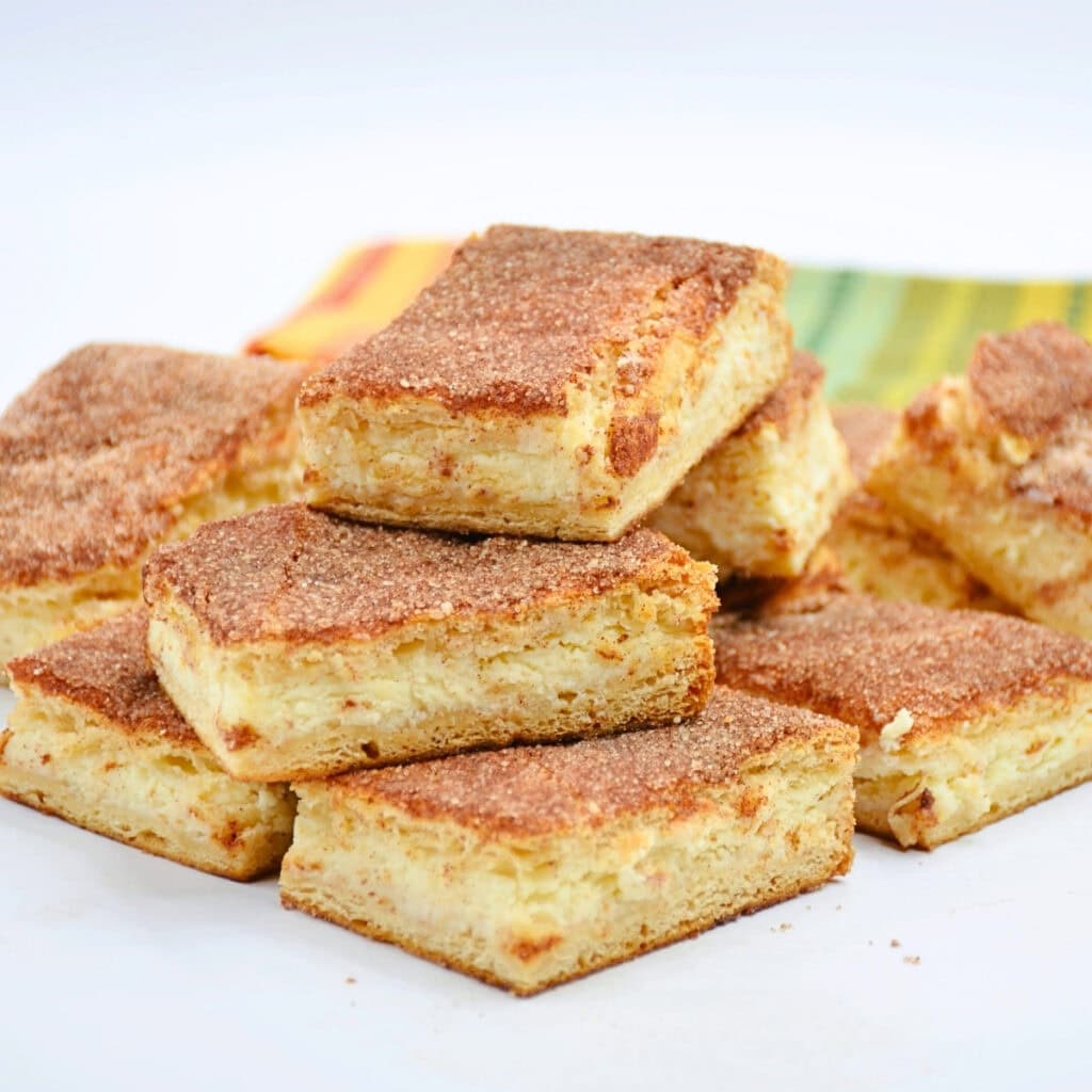 Cinnamon sugar bars stacked on a white plate with a colorful napkin behind.