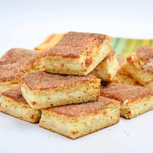 Cinnamon sugar bars stacked on a white plate with a colorful napkin behind.