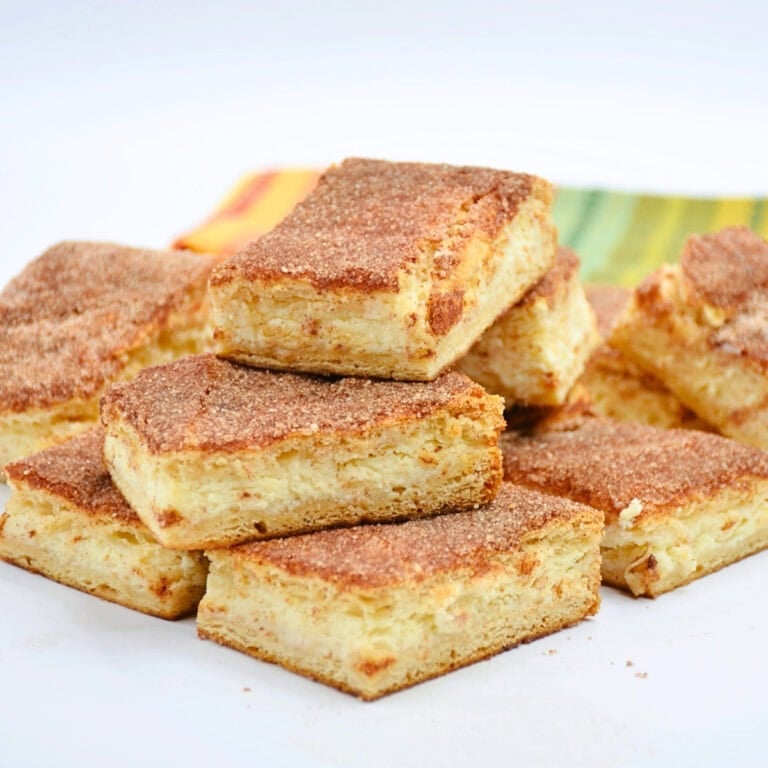 Cinnamon sugar bars stacked on a white plate with a colorful napkin behind.