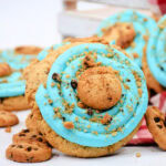 Cookie with blue icing, chocolate chips, and a mini cookie on top.