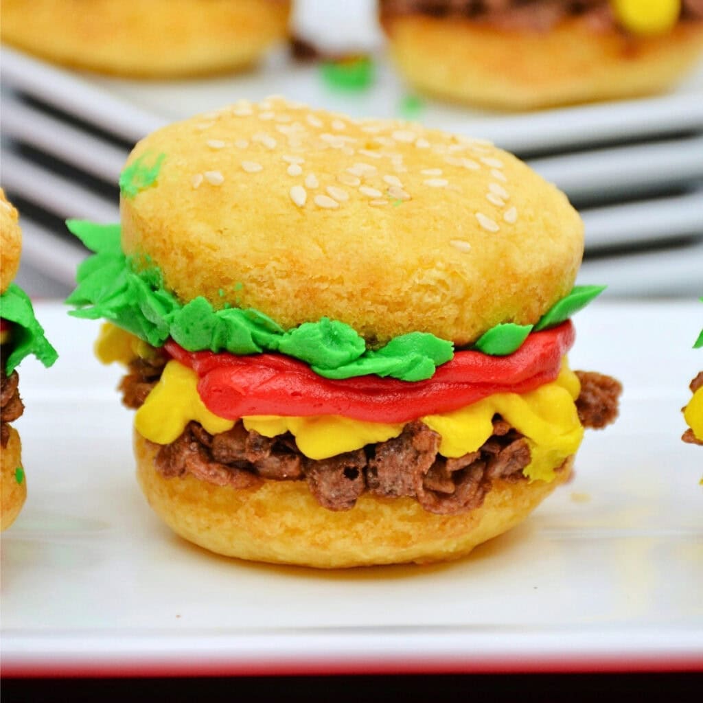 A cupcake decorated to look like a hamburger with icing and toppings.