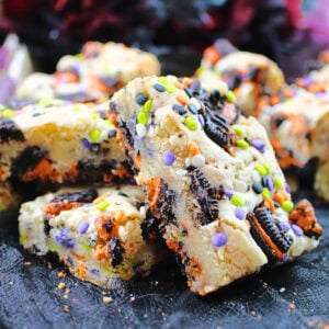 Blondie bars with cookies and colorful sprinkles on a dark surface.