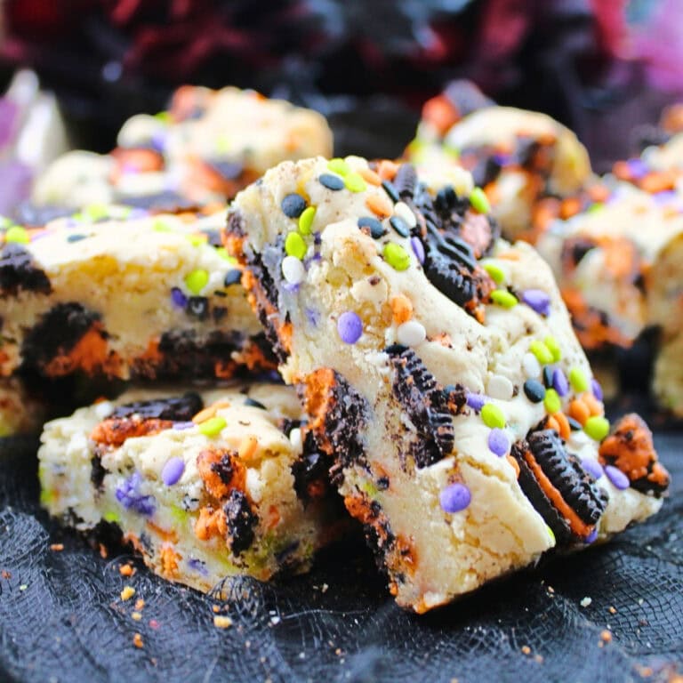 Blondie bars with cookies and colorful sprinkles on a dark surface.