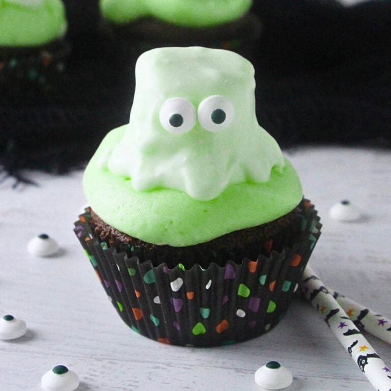 Cupcake with green frosting and a cute ghost-shaped marshmallow on top.