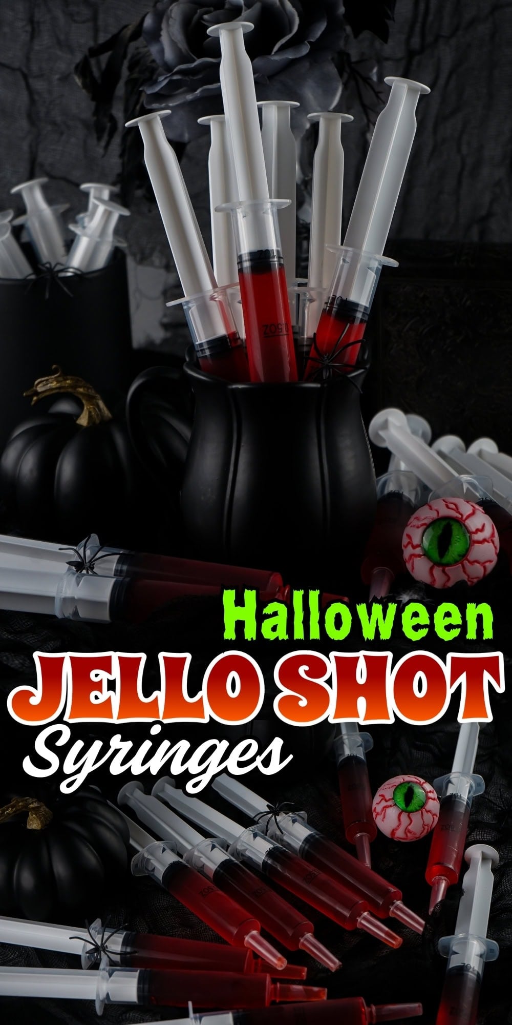 Black pitcher filled with red jello shot syringes, pumpkins, and fake eyeballs.