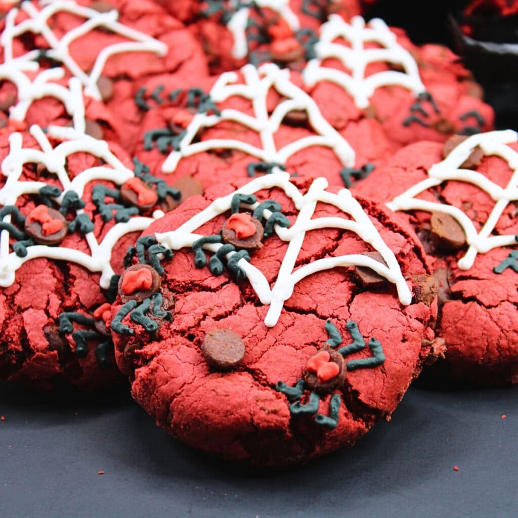 Red cookies with white spiderweb icing and black and red decorative details.