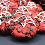 Red cookies with white spiderweb icing and black and red decorative details.