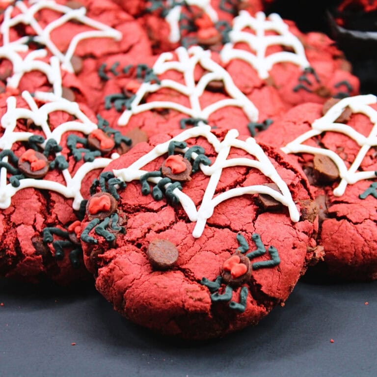 Red cookies with white spiderweb icing and black and red decorative details.