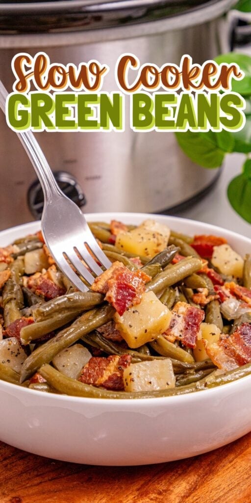 Bowl of green beans, potatoes, and bacon with a fork, slow cooker in background.