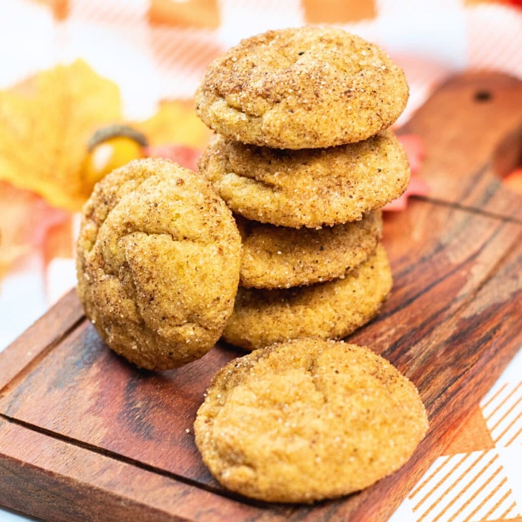 Stack of cinnamon sugar cookies on a wooden board with fall decor.