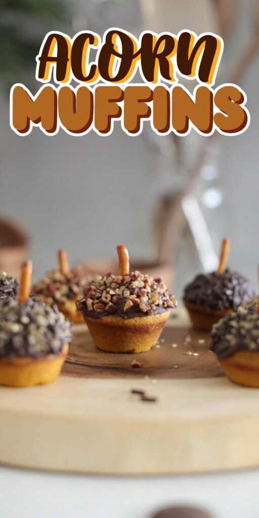 Mini muffins decorated as acorns with pretzel stems on a wooden board.