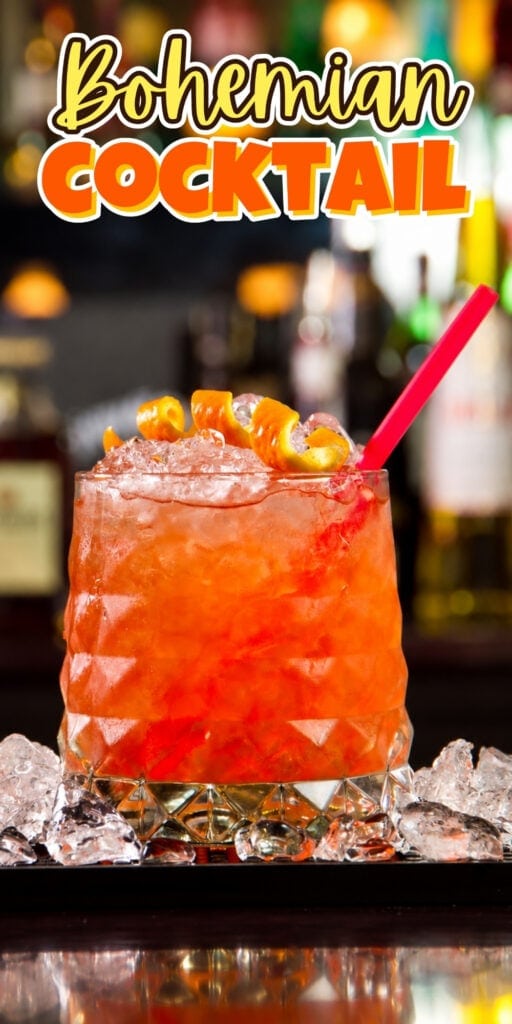 Orange cocktail with ice, orange peel garnish, and a red straw on a bar.
