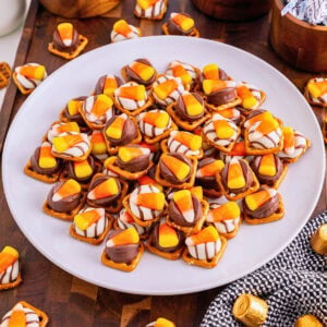 Plate of pretzel snacks topped with melted chocolates and candy corn pieces.