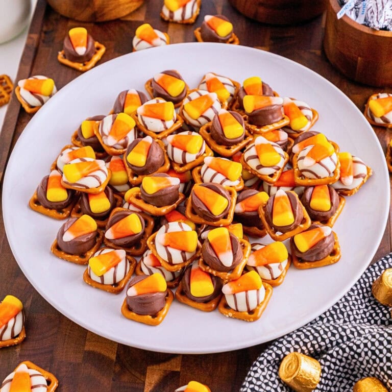 Plate of pretzel snacks topped with melted chocolates and candy corn pieces.