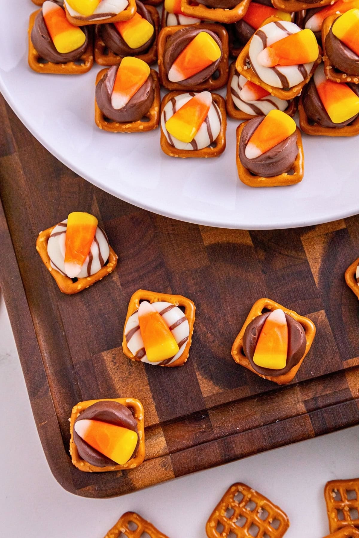 Pretzel squares topped with chocolate, white drizzle, and candy corn on a board.