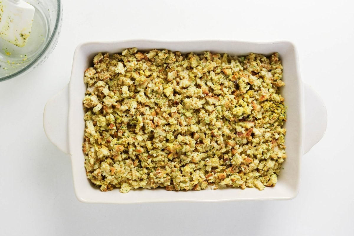 White baking dish filled with breadcrumb stuffing on a white background.