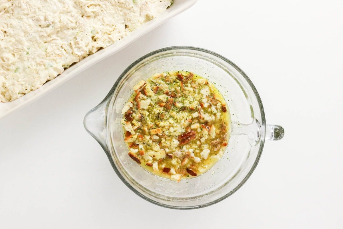 Glass bowl with mixed seasoning and chopped vegetables next to a casserole dish.