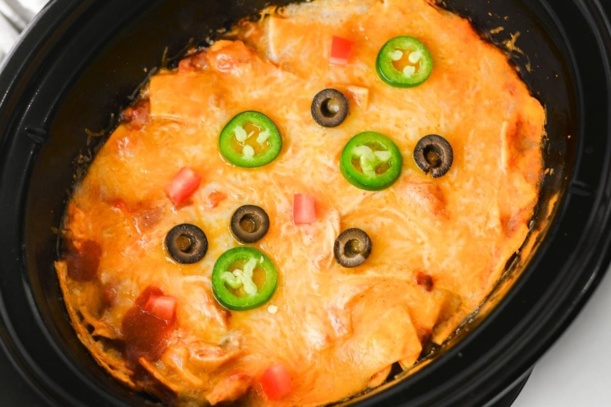 Casserole topped with cheese, jalapeño slices, olives, and diced tomatoes.