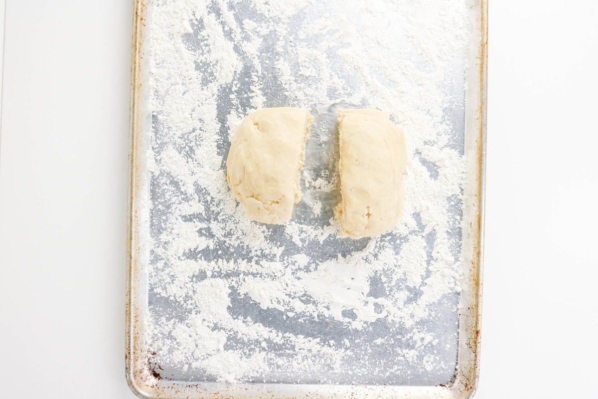 Two pieces of dough on a floured baking sheet.