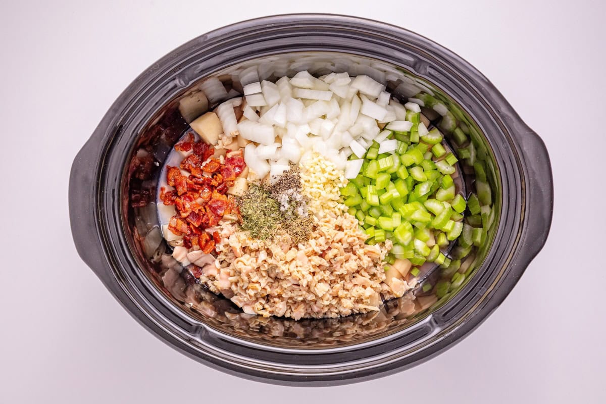 Chopped onion, celery, garlic, clams, tomato, and spices in a slow cooker.